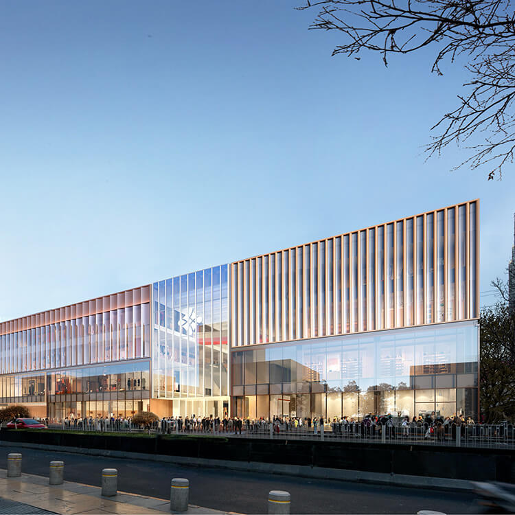 Building exterior with glass facade and wooden accents, featuring a crowd gathered outside at dusk. Architectural design emphasizing openness.