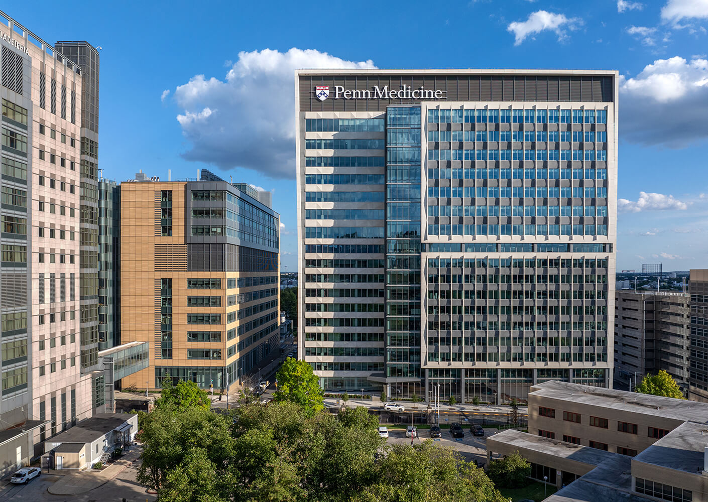 Office building of Penn Medicine, showcasing a sleek facade with multiple glass windows, surrounded by other commercial structures and greenery.